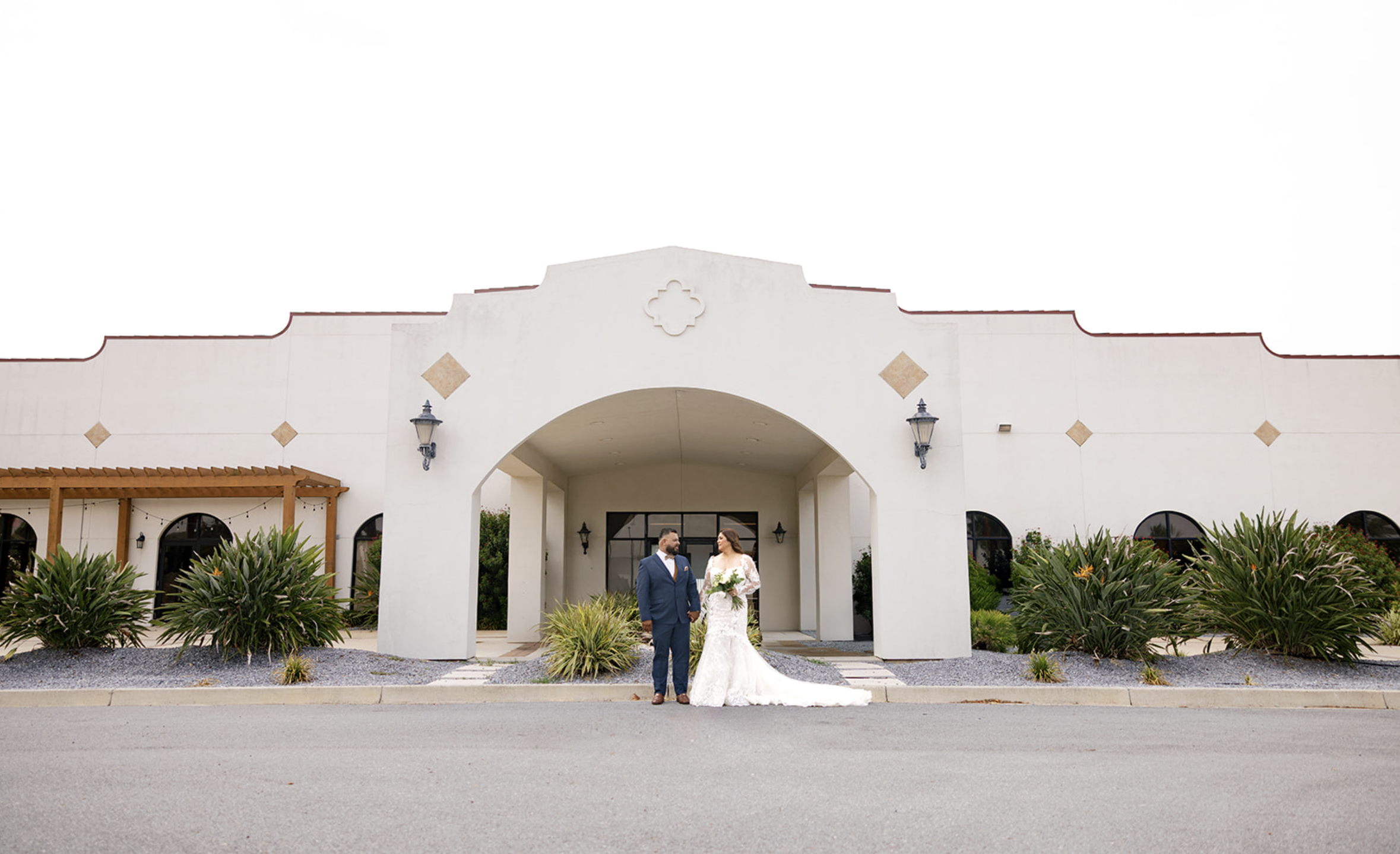 Bride and groom posing in front of their wedding venue, captured by San Antonio wedding photographer Angie Rich.
