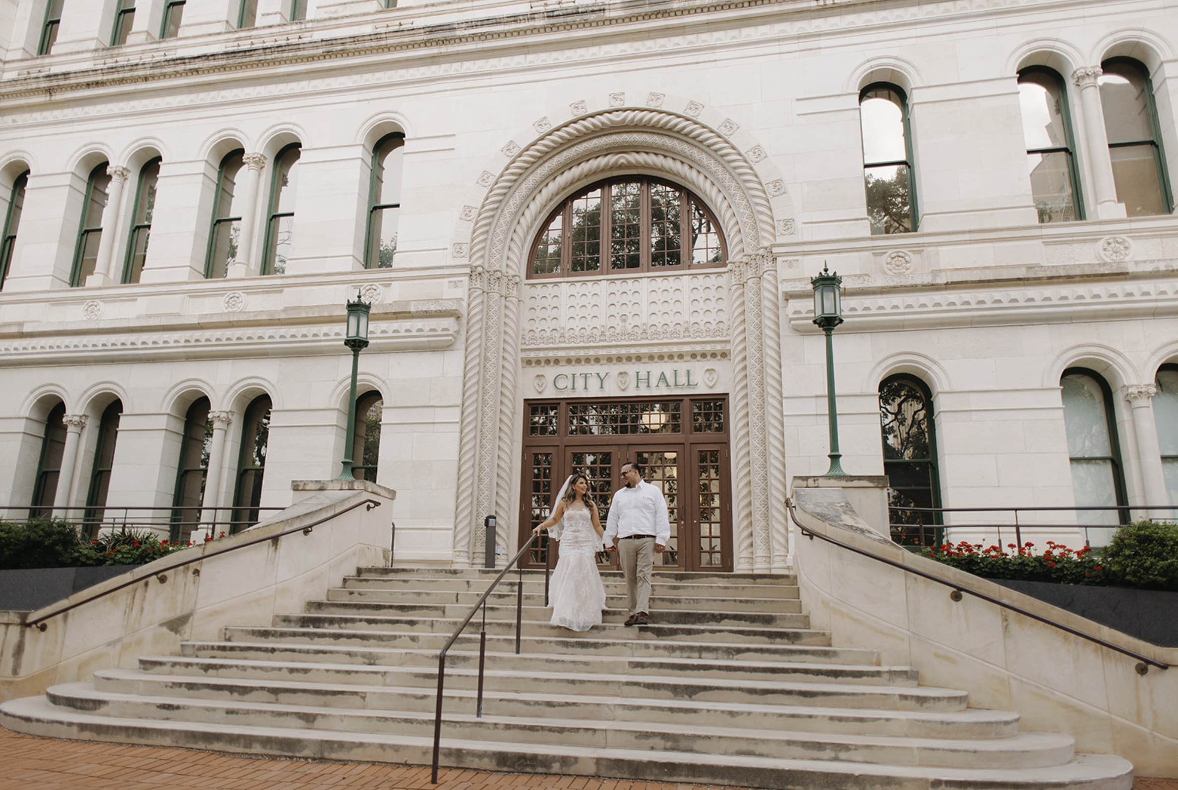 Newlywed couple walking down the stairs of San Antonio City Hall after their downtown elopement, captured by San Antonio wedding photographer Angie Rich.