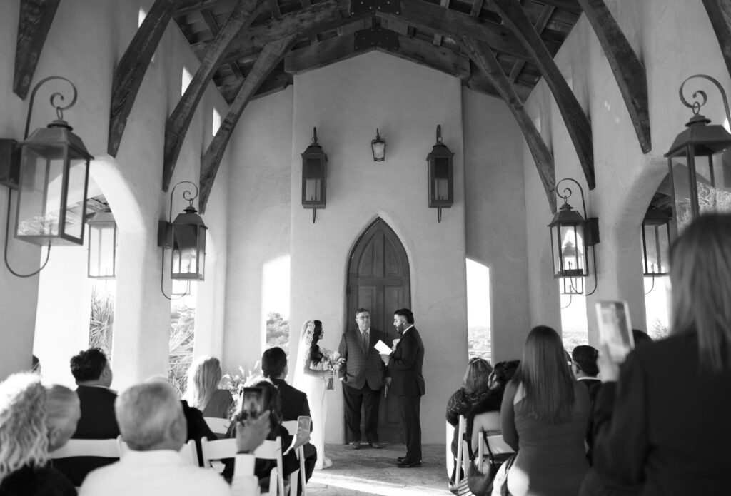 Black and white photograph of an intimate wedding ceremony inside Chapel Dulcinea overlooking the Texas Hill Country.